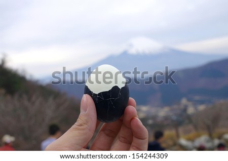 hold black boiled egg with Fuji mountain background, Fuji Hakone park in Japan,