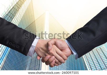 Hand shake between a businessman on Modern glass building background