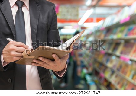 Businessman writing the note book on Abstract blurred photo of book store background