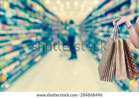 Holding shopping bags by hand on Supermarket blur background with bokeh, Miscellaneous Product shelf