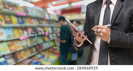 Businessman writing the note book on Abstract blurred photo of book store with people background