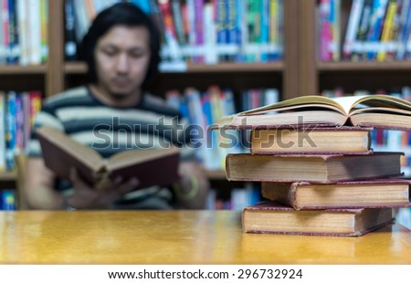 old book on the desk in library with the man reading the book background