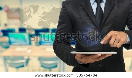 Businessman using the tablet on Abstract blurred photo of empty computer room with earth and world map,Elements of this image furnished by NASA, education and business concept