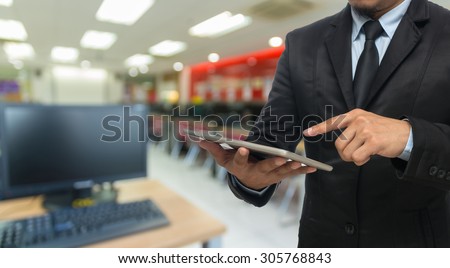Businessman using the tablet on Abstract blurred photo of empty computer room, education and business concept