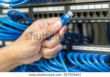 hand holding network cable connect to router and switch hub in server room