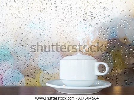 White coffee cup with smoke on the wooden table and water drop grass