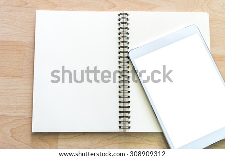 Tablet on open leather book with wooden background