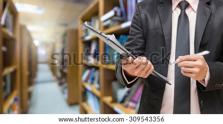 Businessman writing the file pad on the Abstract blurred photo of library background