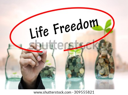 Man Hand writing Life Freedom by black marker on visual screen. Business concept