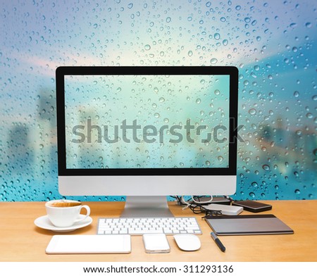Workspace with computer desktop on the wood table with a glass surface windows with cityscape background