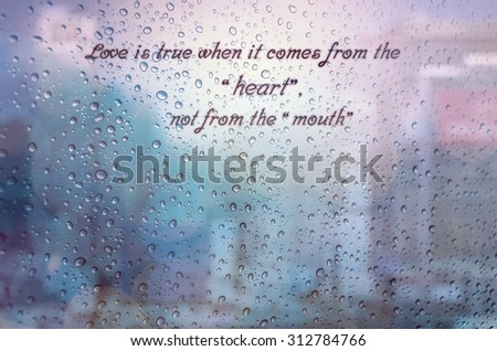 Waterdrops on a glass surface windows with Love from heart qoutes on cityscape background