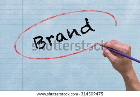 Hand writing Brand by pencil on paper Notebook background. Business and Education concept