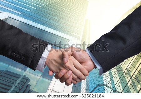 Hand shake between a businessman on Modern glass building background, Business agreement concept