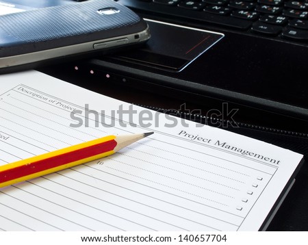 Project management paper with laptop and pencil