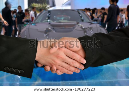 Business handshake with car exhibition background