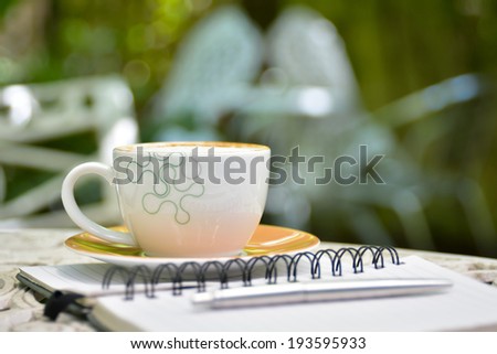 Cappuccino coffee with note book on white table
