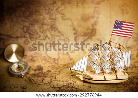 Sailboat model with flag on ancient world map, vintage light tone