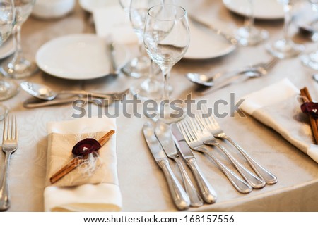Place setting for special event with silver flatware, beige napkin and cinnamon decoration