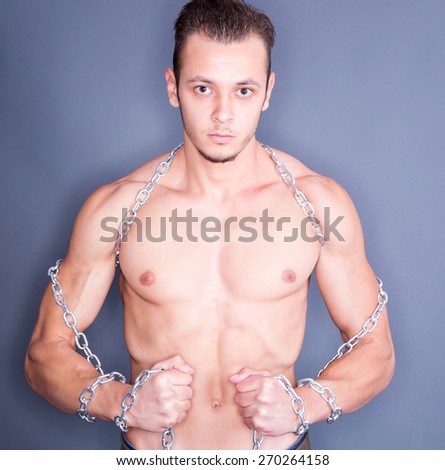 Serious shirtless naked man with steel chain around neck and arms. Bodybuilding