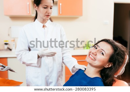 Female dentist consulting happy patient in modern dental office.