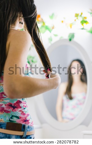 Blurry pose of a woman holding her hair and looking in the mirror. Focus on the back of the woman