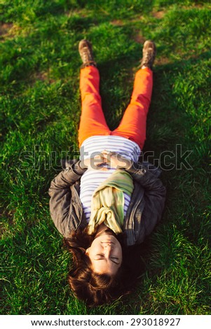 Closeup portrait of brunette girl lying upside down on grass
