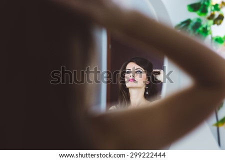 Portrait of a beautiful woman looking in the mirror and holding her hair with hand