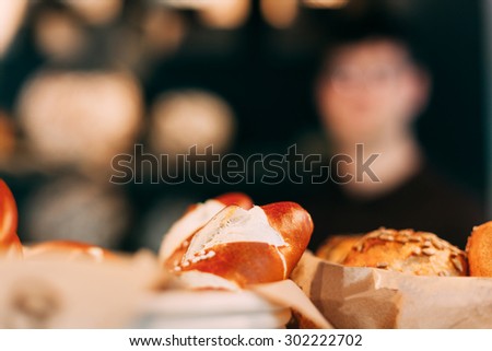 Bread rolls close-up in a bakery, the baker image blurred