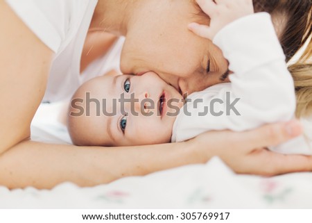 Closeup of a mother biting her baby boy\'s cheek