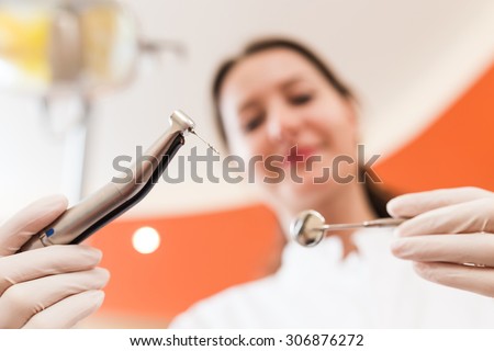 Female dentist using a drill for the root canal treatment.