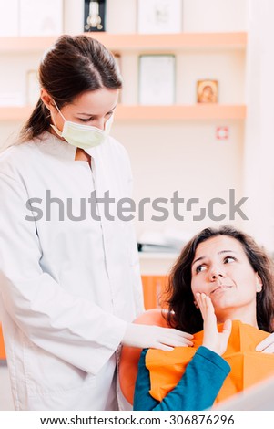 Patient with tooth pain is being calmed down by a female dentist and prepared for examination.