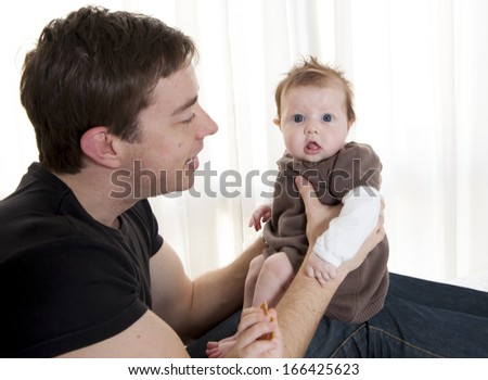 Young father holding his baby girl on surprised expression