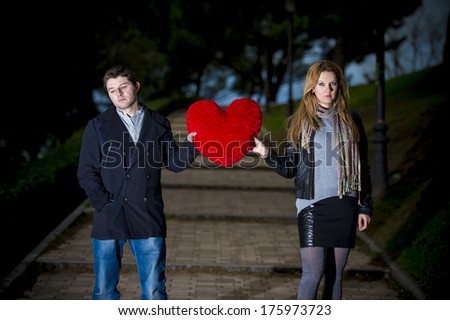 young attractive couple fighting over a love hearted shaped pillow