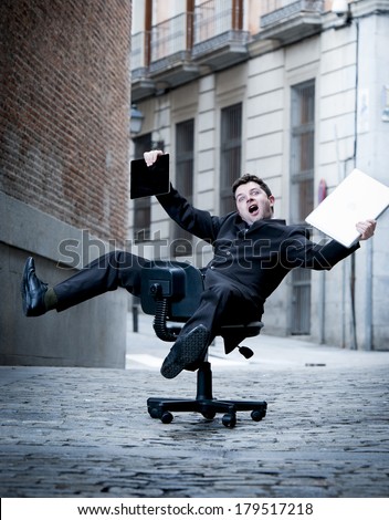 crazy overworked  business man rolling downhill on chair with computer and tablet