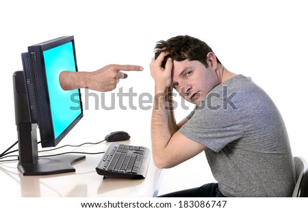 young worried man in stress with computer and hand with finger pointing him in social network media cybermobbing and bullying