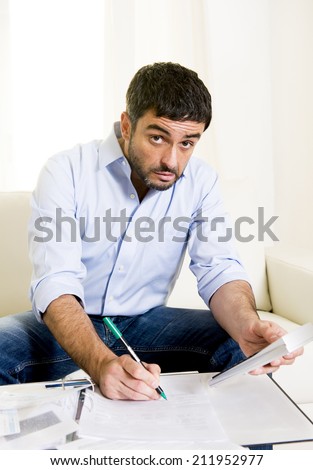 young attractive latin american business man at home sitting on sofa in stress with credit card and calculator accounting debts, bills and bank papers worried for money and financial situation
