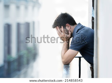 Lonely young man outside at house balcony looking depressed, destroyed, sad and suffering emotional crisis and grief in work and personal life problem on an urban background