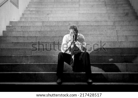 Young business man crying abandoned lost in depression sitting on ground street concrete stairs suffering emotional pain, sadness, looking sick in grunge lighting