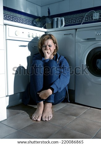 lonely depressed and sick woman sitting alone crying on kitchen floor in stress suffering depression and sadness feeling miserable in barefoot looking desperate