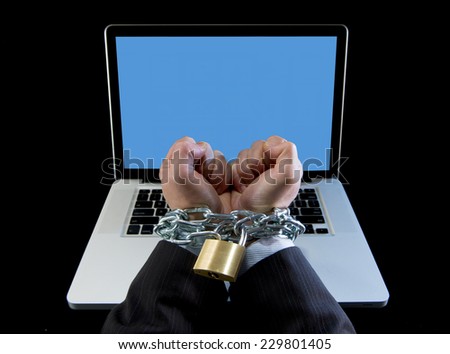 Hands of caucasian businessman addicted to work bond and locked with iron chain handcuffed to computer laptop in workaholic, internet slave and addict concept