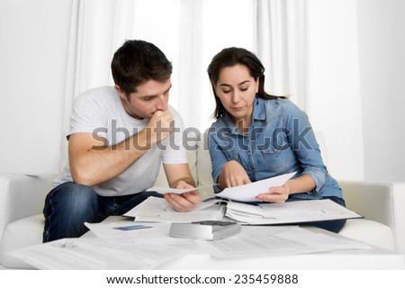 young couple worried home in stress sitting at living room couch accounting debt bills bank papers expenses and payments feeling desperate in bad financial situation