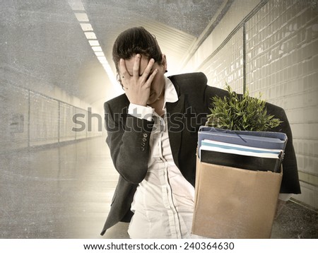 desperate depressed businesswoman fired from job carrying office belongings in cardboard box crying sad in grunge tunnel background in financial crisis and work loss concept