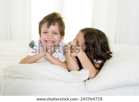 Brazilian 7 years old little girl playing on bed or couch together with her 4 years old small brother smiling happy in brotherhood and children lifestyle concept