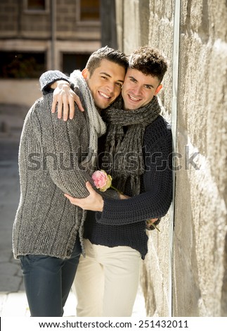 young happy attractive gay men couple holding rose hugging having fun  outdoors on street in free homosexual love concept in Valentines day on urban background