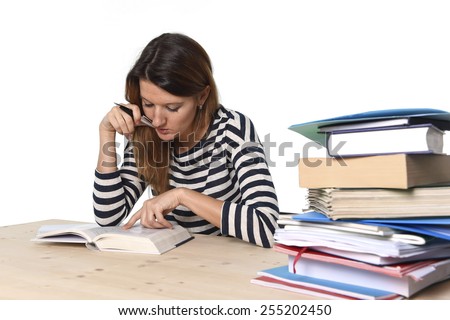 young student girl concentrated studying with textbook at college library desk with piles of books preparing MBA test or exam in academic wisdom and education concept