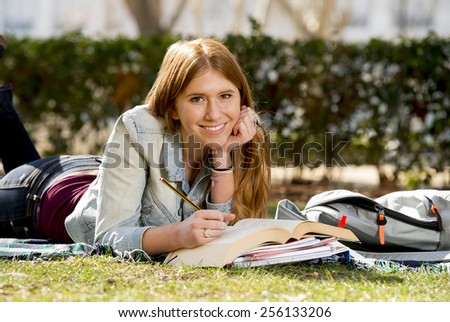 young beautiful student girl lying on campus park grass with books on rug studying happy preparing exam in university and college education concept