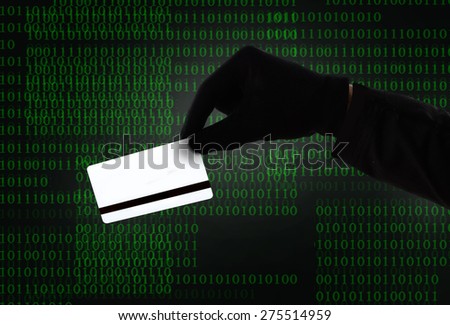 hacker hand in black glove holding credit card in binary code computer screen background  in cyber and digital crime, hacking, cybercrime and illegal activity concept