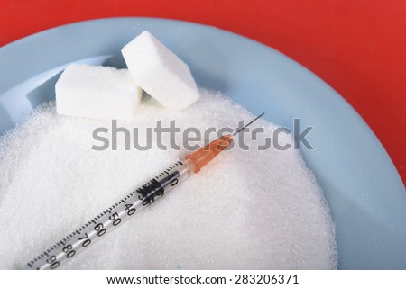dish full of white sugar and cubes with syringe in sugar addiction and abuse concept, unhealthy nutrition and sweet excess