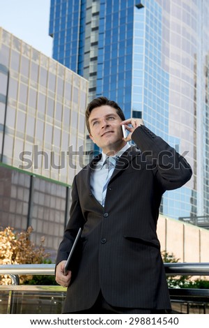 young attractive businessman in suit and necktie talking on mobile smart phone listening carefully standing outdoors on financial district smiling happy in business success concept