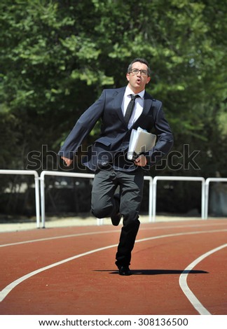 businessman in suit and necktie carrying folder portfolio and files running in stress on athletic track looking tired and stressed in work urgent problems concept